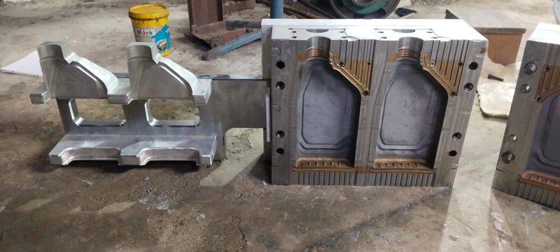 Two-cavity blow mould for a one litre lubricant bottle, shown with its cavity and backing halves.