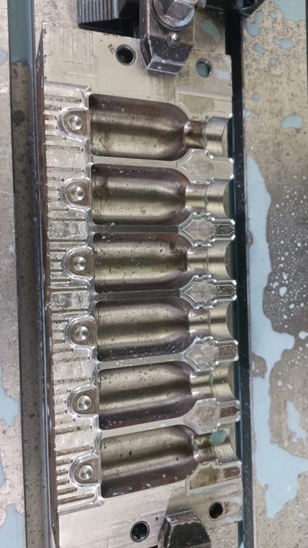 Six-cavity bottle mould, photographed on the machine with the cavities polished.