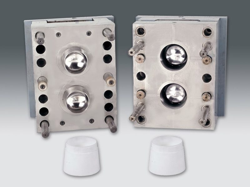 Two-cavity injection mould for a threaded closure, shown with the moulded caps.